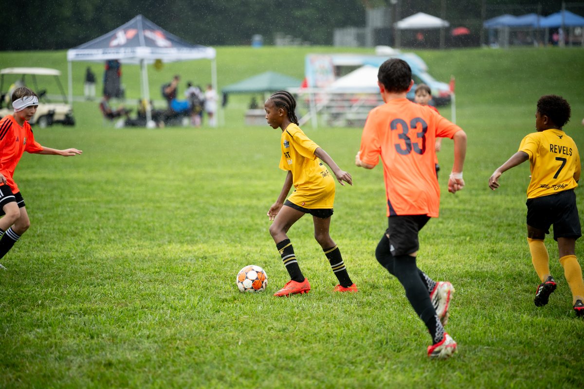 Travel Elite players in yellow driving toward the ball