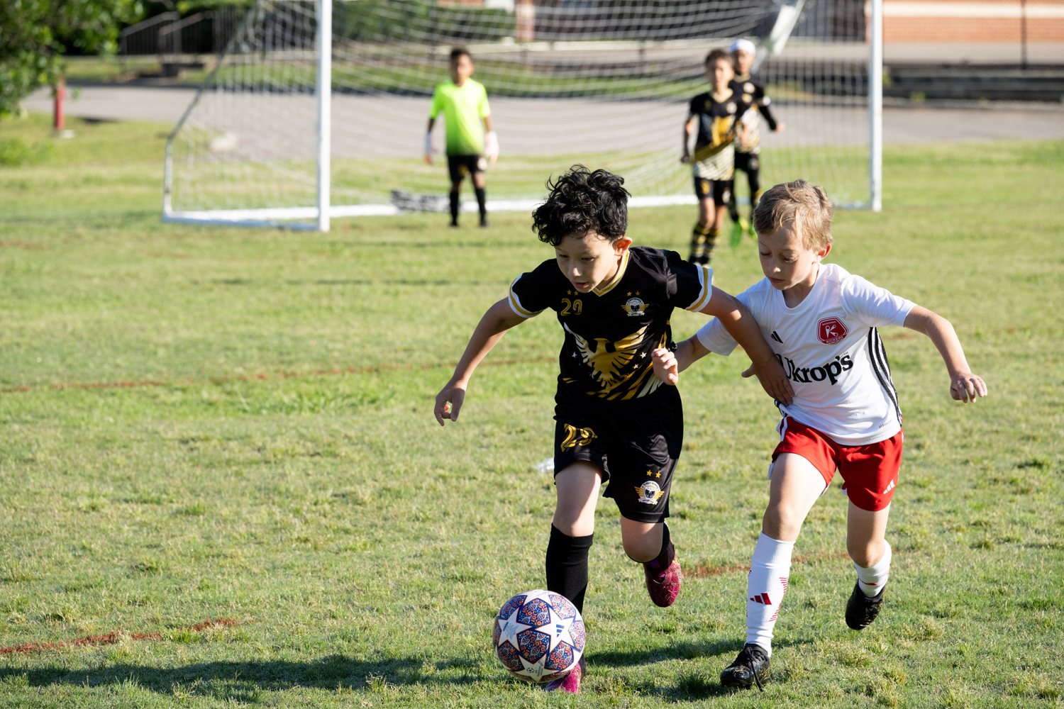 Flight School Project player in black and gold driving past a defender